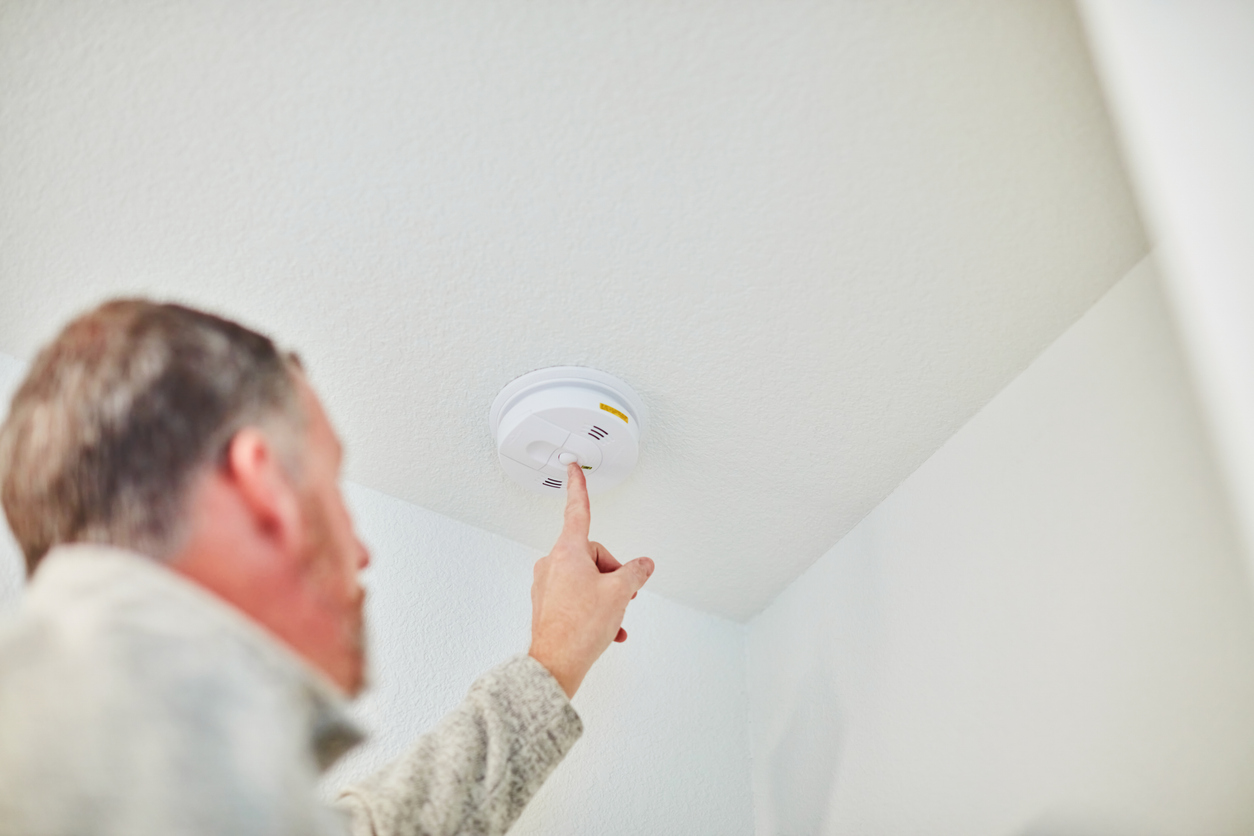 Homeowner checking a carbon monoxide (CO) detector to ensure home safety and early detection of harmful gases.