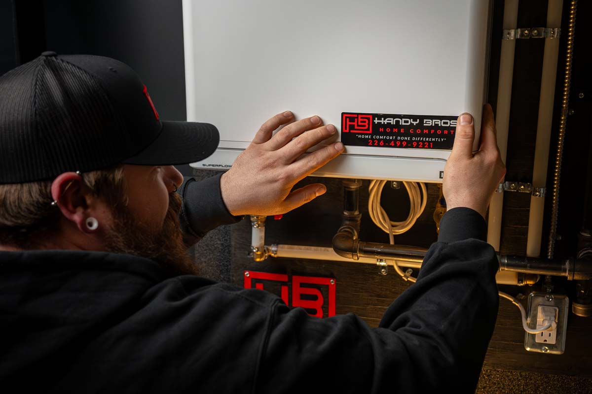 A Handy Bros. technician applying branding to a tankless water heater, showcasing quality service and professional installation.