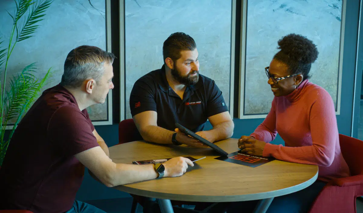 A Handy Bros. professional sitting with a couple, presenting HVAC options and building trust through clear communication and expert guidance.