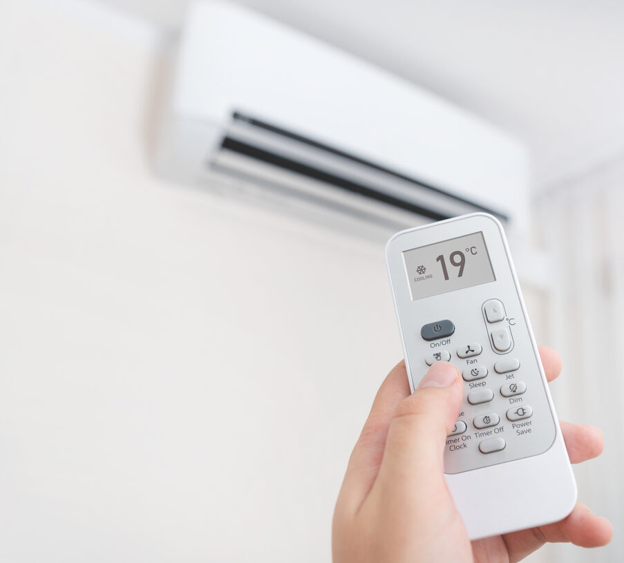 A ductless AC remote control being used to adjust temperature settings for optimal indoor comfort and energy efficiency.