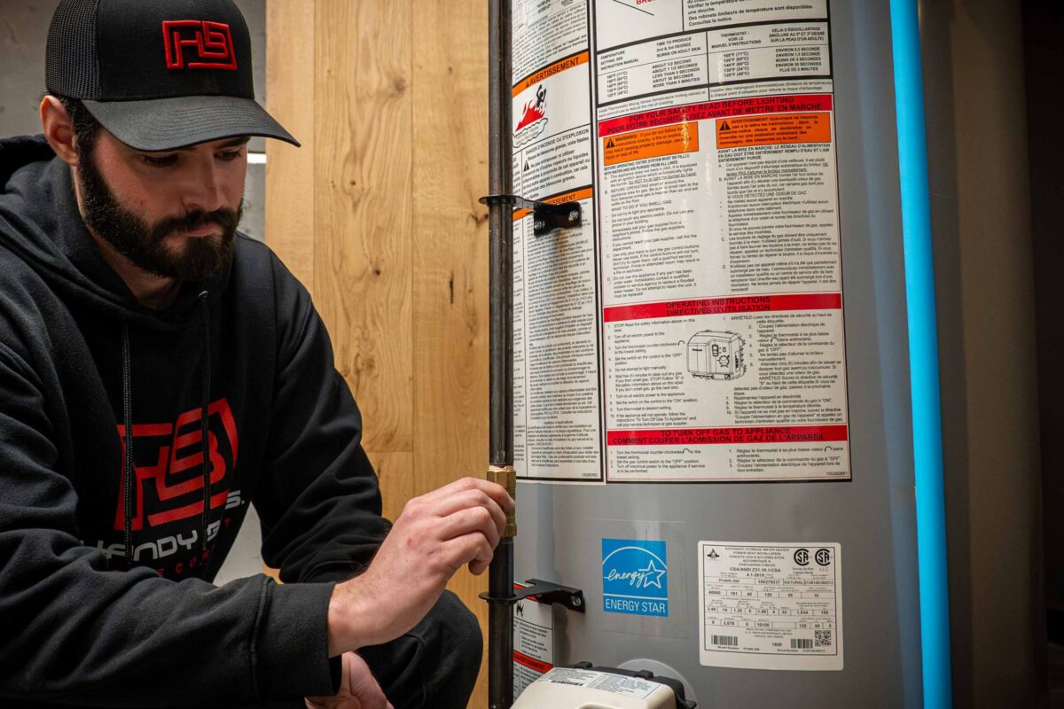 A technician using tools to perform a repair on a residential water heater system.