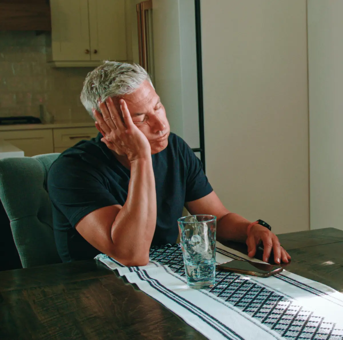 no-cooling-1-2-e1738860100541-hermes-nonmp4-1400 - handy bros. home comfort - handy bros. home comfort Man with gray hair sits at a dining table, resting his head on his hand, looking fatigued or asleep.