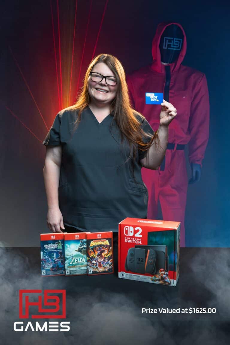 Smiling woman in scrubs holds a Best Buy gift card, with Nintendo Switch box and game cases on a table in front.