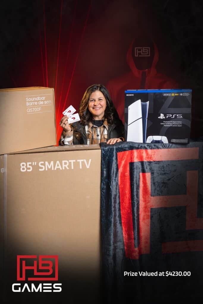 Smiling woman behind large prize boxes, including an 85-inch smart TV and a PS5 box, holding game cards.