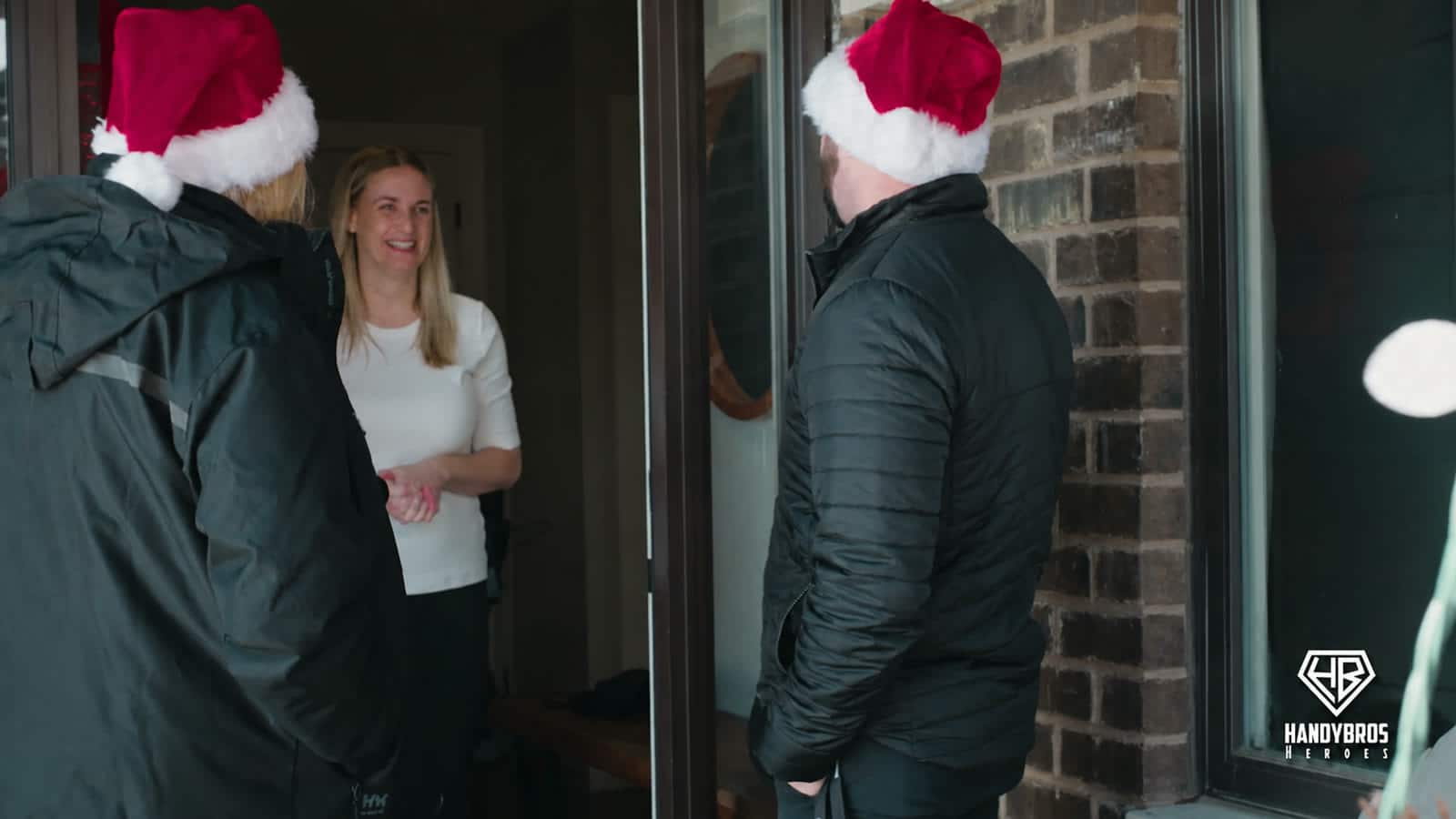 Amanda smiles at the door as the Handy Bros. Heroes team arrives to share the Christmas surprise.