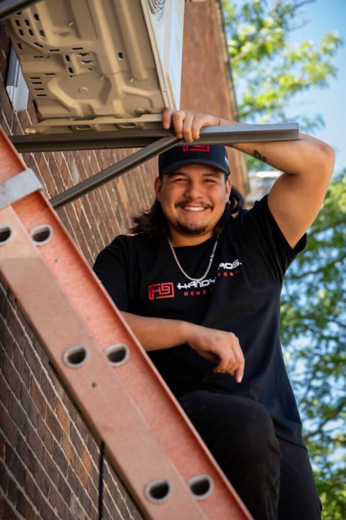 Handy Bros. technician securing a wall bracket beneath a ductless outdoor unit.