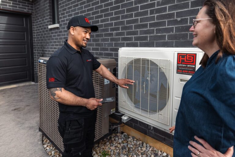 Handy Bros. technician showing a homeowner an outdoor heat pump.