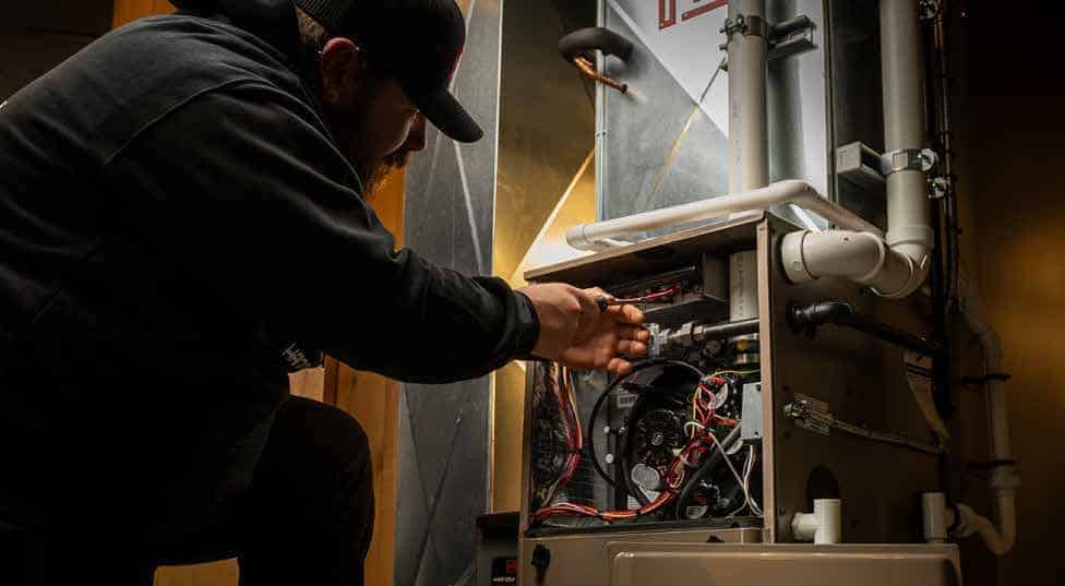 october tuneup deal - handy bros. home comfort Technician servicing a furnace in Handy Bros October flyer